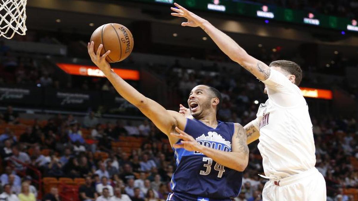 Dallas Mavericks guard Devin Harris, left, goes up for a shot against Miami Heat guard Tyler Johnson in first-half action of Thursday’s game in Miami.