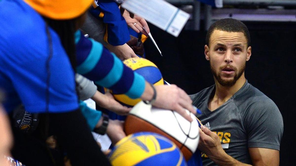 The Golden State Warriors’ Steph Curry, signing autographs in September, consoled Devin Harris’ 9-year-old nephew before a game against the Mavericks Monday. Harris’ older brother died after a car wreck in Dallas last week.