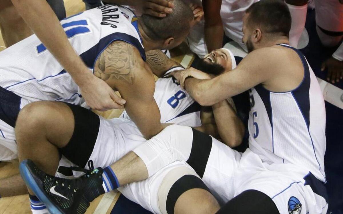 Dallas Mavericks guard Deron Williams is mobbed by teammates after hitting the game-winning shot at the second-overtime buzzer.