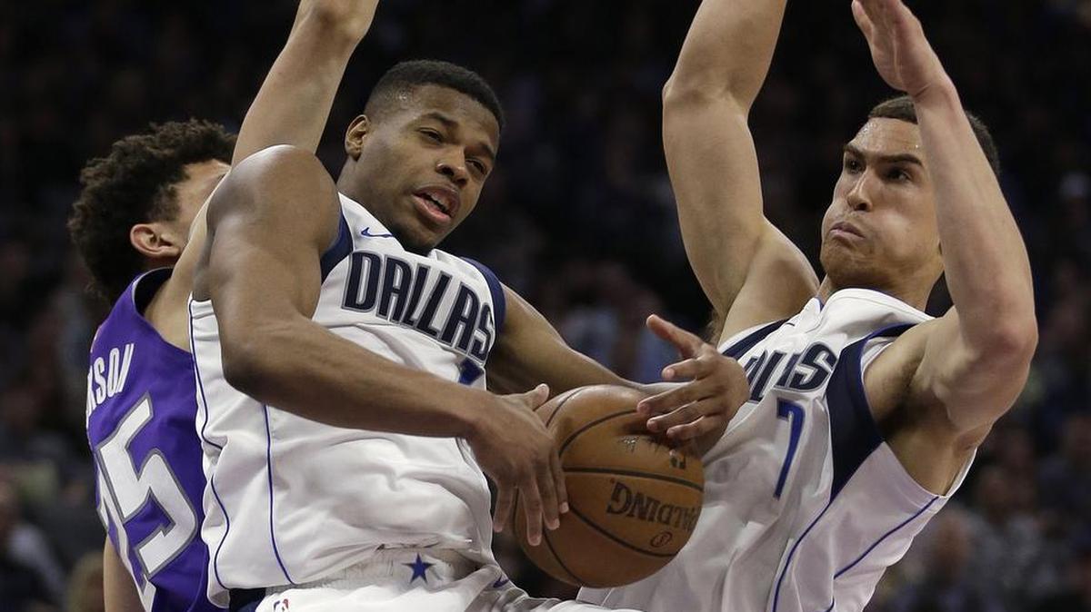 Dallas Mavericks guard Dennis Smith Jr., center, grabs a rebound between Sacramento Kings forward Justin Jackson, left, and Mavericks forward Dwight Powell during the second half of an NBA game Saturday, Feb. 3, 2018, in Sacramento, Calif. The Mavericks won 106-99.
