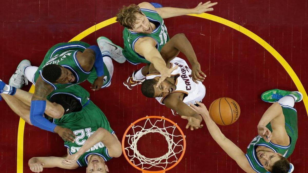 Mavericks star Dirk Nowitzki, top, battles the Cavaliers’ Tristan Thompson, second from right, on his drive to the basket Wednesday night as Mavs forward David Lee takes a tumble at left. Nowitzki has been the Mavs’ man in the middle of late, playing center.