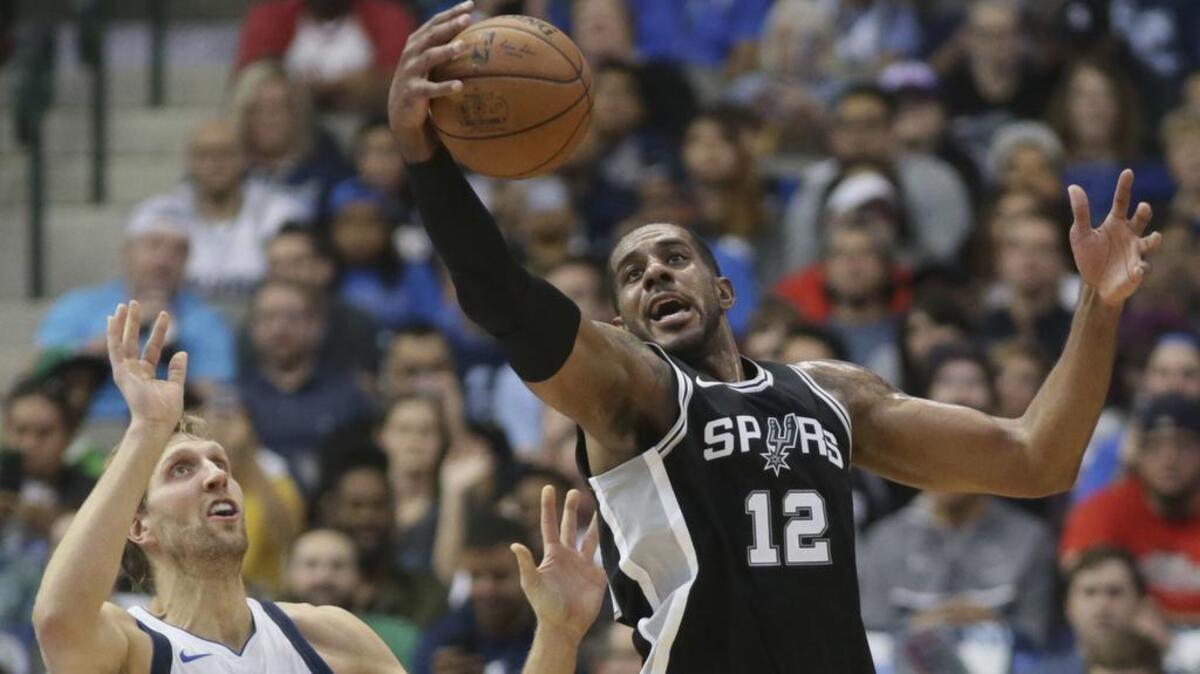 San Antonio Spurs forward LaMarcus Aldridge (12) grabs the ball in front of Dallas Mavericks forward Dirk Nowitzki during Tuesday’s first half.