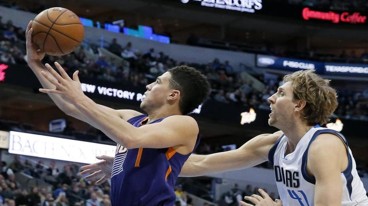 Young Suns guard Devin Booker, left, coasts past Mavericks center Dirk Nowitzki for two of his 22 points in Thursday’s Phoenix victory.