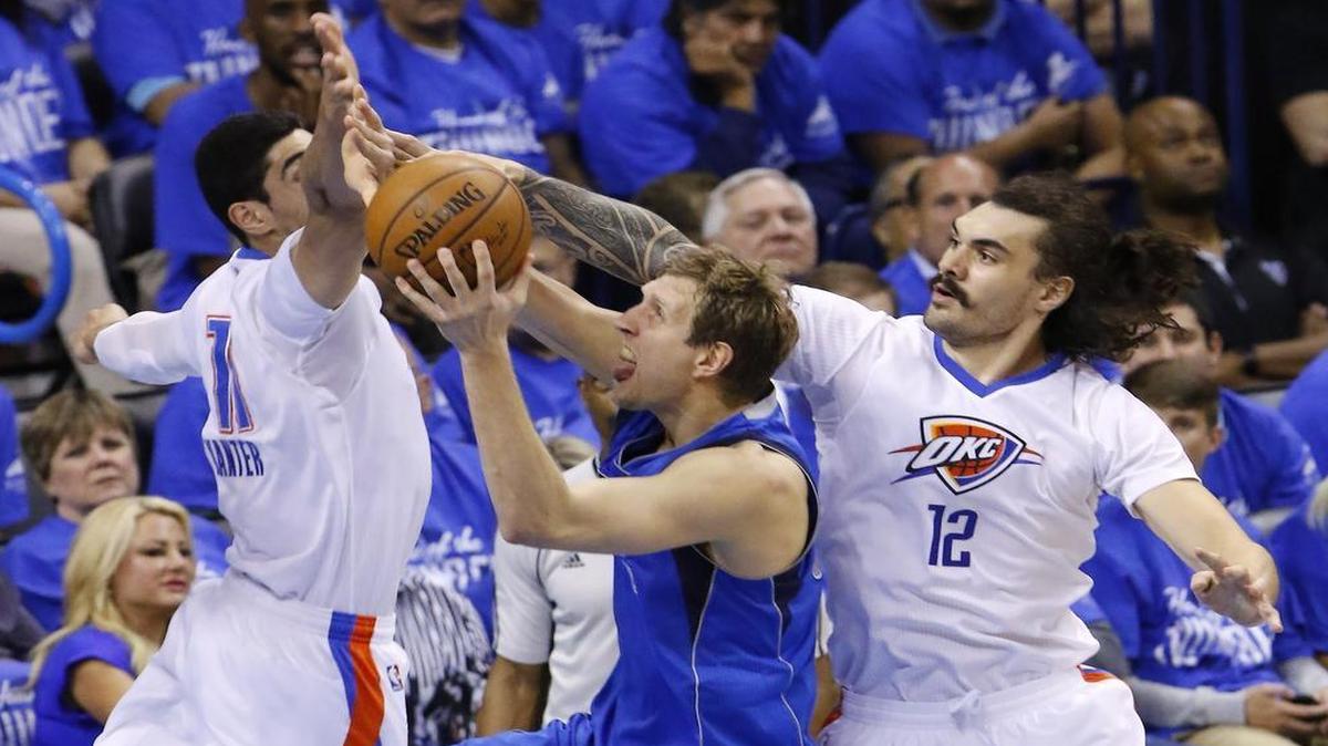 The Mavericks’ Dirk Nowitzi tries to go through Enes Kanter, left, and Steven Adams on the way to the basket.