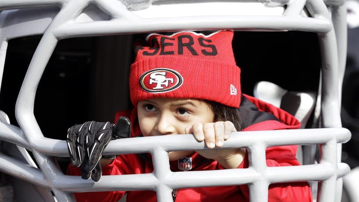The NFL draws attention from all ages. Mason Lopez, 4, looks out through an oversized Dallas Cowboys football helmet at the NFL Experience at Super Bowl 50.