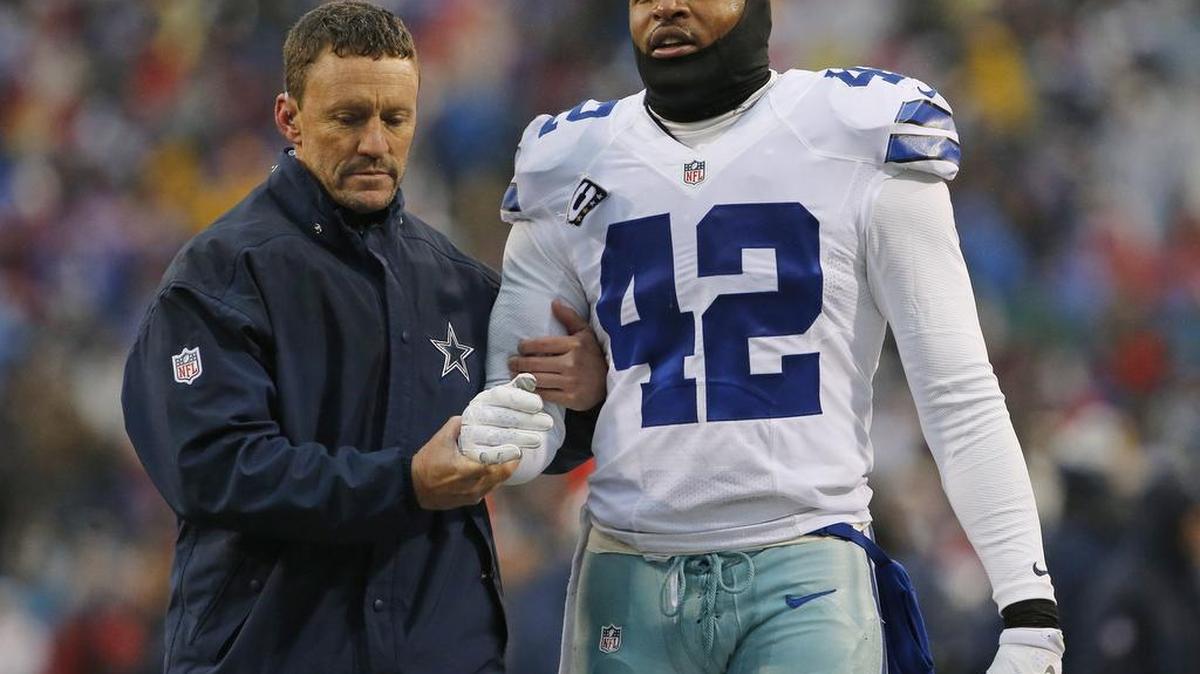 Athletic trainer Britt Brown helps Cowboys safety Barry Church (42) off the field after Church broke his arm.