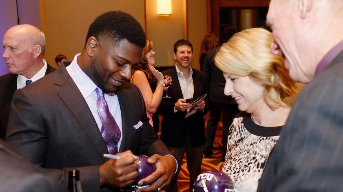 Former NFL and TCU running back LaDainian Tomlinson (from left) signs mini TCU helmets for Linda Bacsik and former Texas Ranger Mike Bascik Sr. at the Bobby Bragan Gala in the Omni Fort Worth Hotel Wednesday.