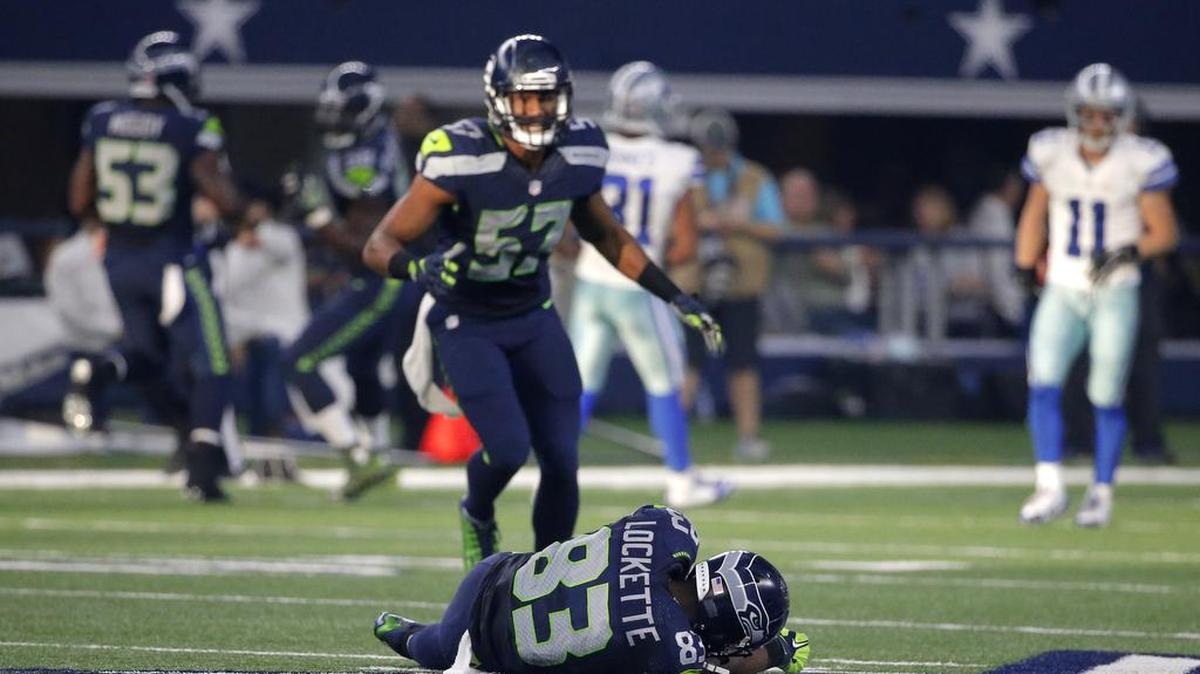 Mike Morgan (57) checks on teammate Ricardo Lockette (83) after the Seattle receiver was knocked unconscious on a blindside block by Cowboys safety Jeff Heath.