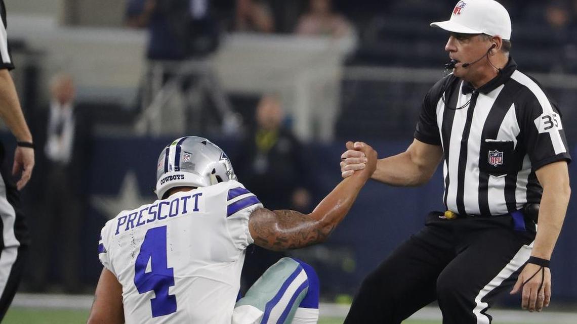 NFL Referee John Hussey helps Dallas Cowboys quarterback Dak Prescott up after he was knocked down after a pass.