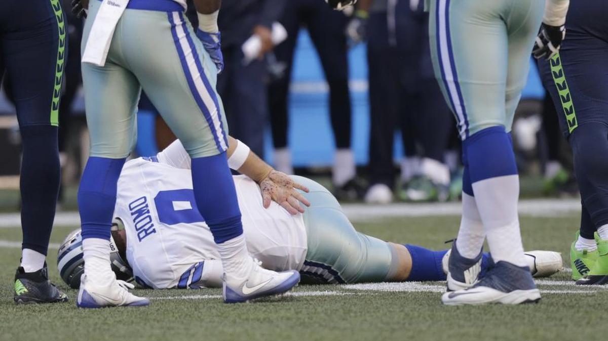 Cowboys quarterback Tony Romo holds his back after he was tackled by Seahawks defensive end Cliff Avril, right, on Aug. 25.