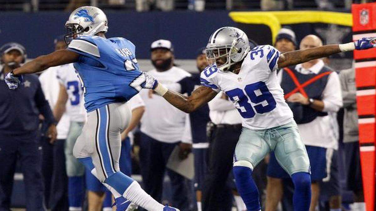 
Detroit Lions running back Reggie Bush (21) is grabbed by Dallas Cowboys cornerback Brandon Carr (39) to stop the run in the third quarter at AT&T Stadium Sunday, January 4, 2015. 
