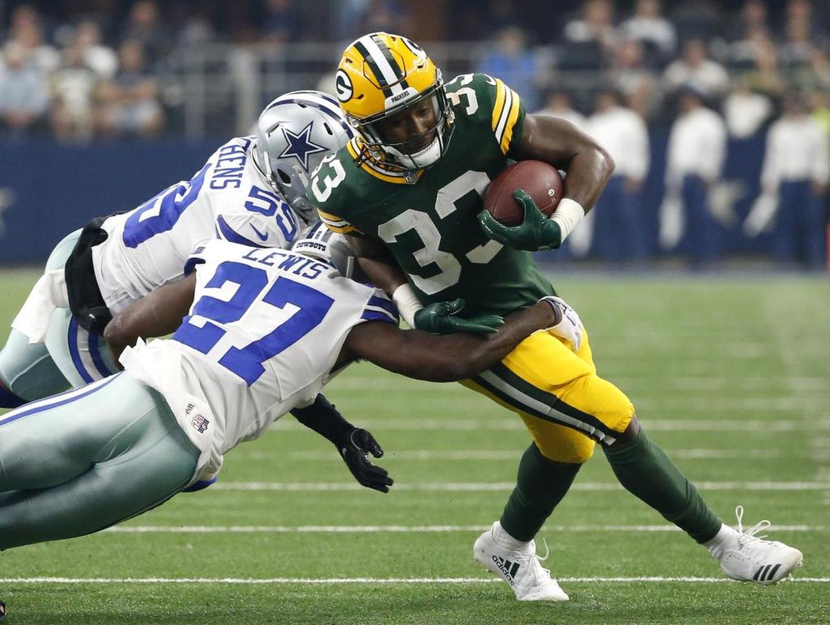 Dallas Cowboys cornerback Jourdan Lewis and linebacker Anthony Hitchens attempt to stop Green Bay Packers running back Aaron Jones as Jones carries the ball in the first half Sunday at AT&T Stadium.
