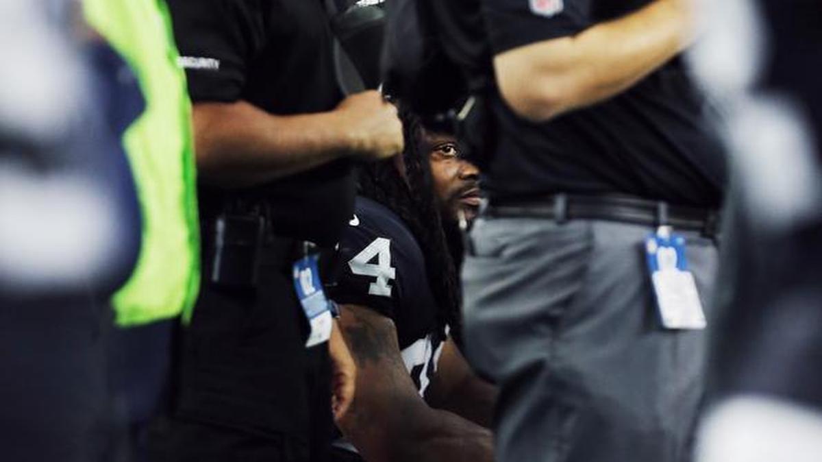 Raiders team personnel surround running back Marshawn Lynch as he sits on the bench during the playing of the national anthem before a game against the Cowboys Saturday night at AT&T Stadium.