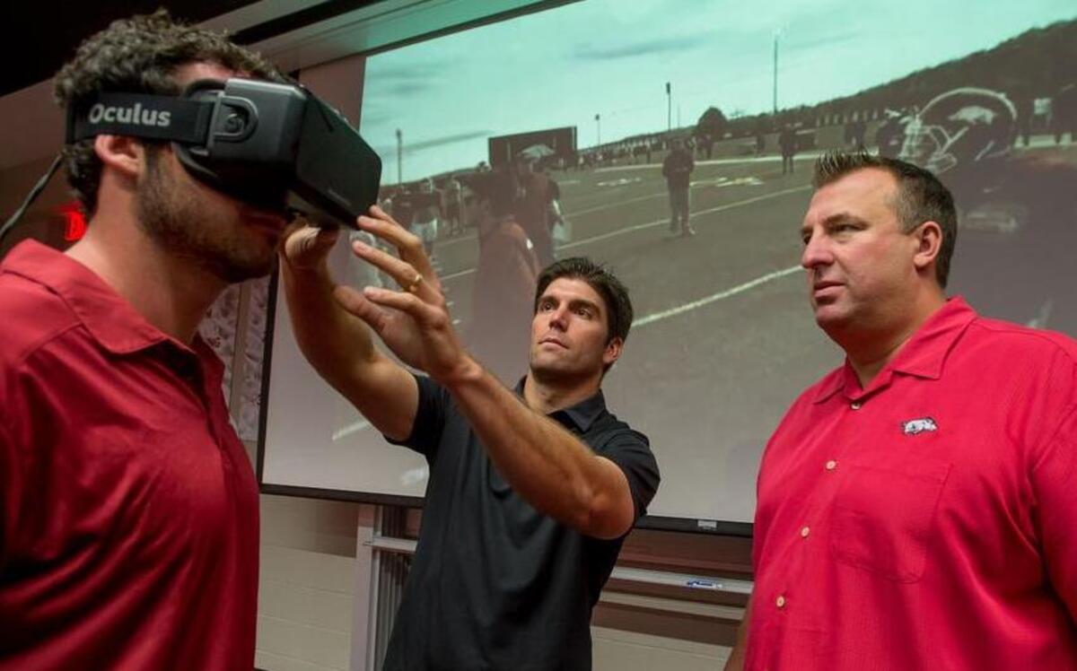 
Derek Belch, center, displays how his virtual reality system works with University of Arkansas football coach Bret Bielema.
