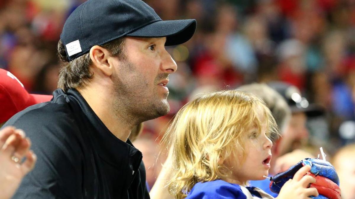 Former Dallas Cowboys quarterback Tony Romo holds his son Rivers as they watch at Rangers game in September 2016 at Globe Life Park.