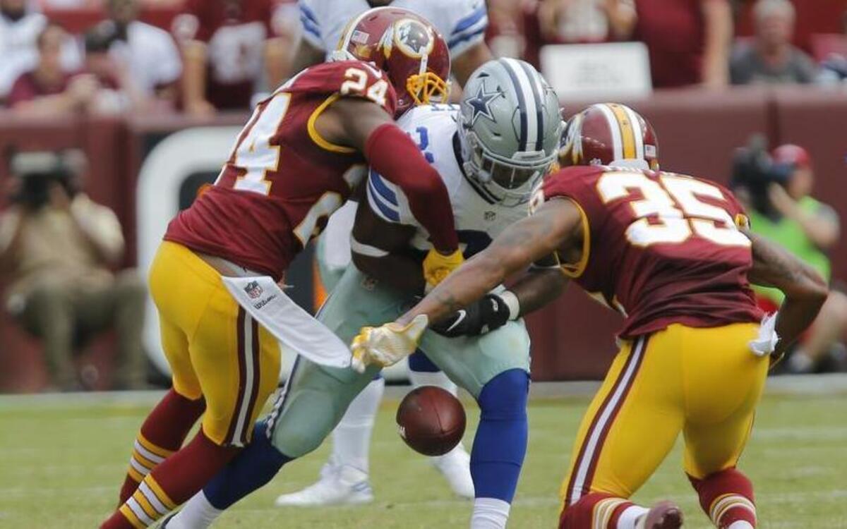Dallas Cowboys running back Ezekiel Elliott (21) fumbles the ball as he is hit by Washington Redskins cornerback Josh Norman (24) and defensive back Dashaun Phillips (35) in the third quarter. Elliott was benched by the Cowboys for the second half of the fourth quarter after fumbling again as the Cowboys won 27-23 Sunday at FedExField.