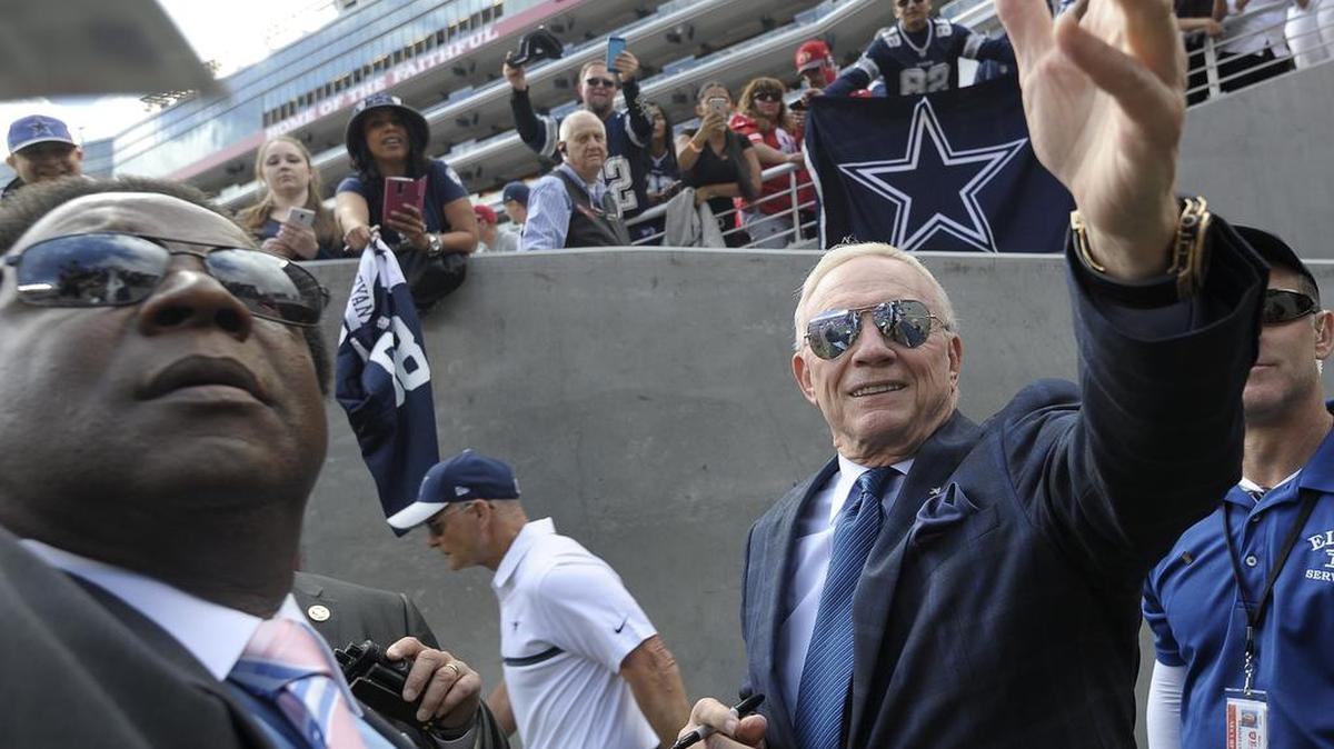 Dallas Cowboys owner Jerry Jones signs autographs after being hit in the head by a helmet a fan threw down.