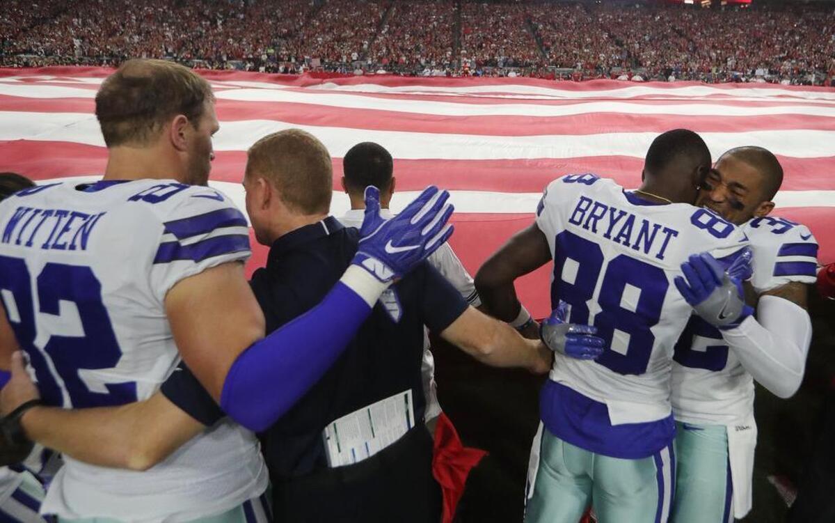 Dallas Cowboys Jason Witten, left, Jason Garrett, Dez Bryant and Orlando Scandrick hug after briefly kneeling together then standing for the National Anthem before Monday’s game against the Arizona Cardinals in Glendale, Ariz., on Sept. 25, 2017.