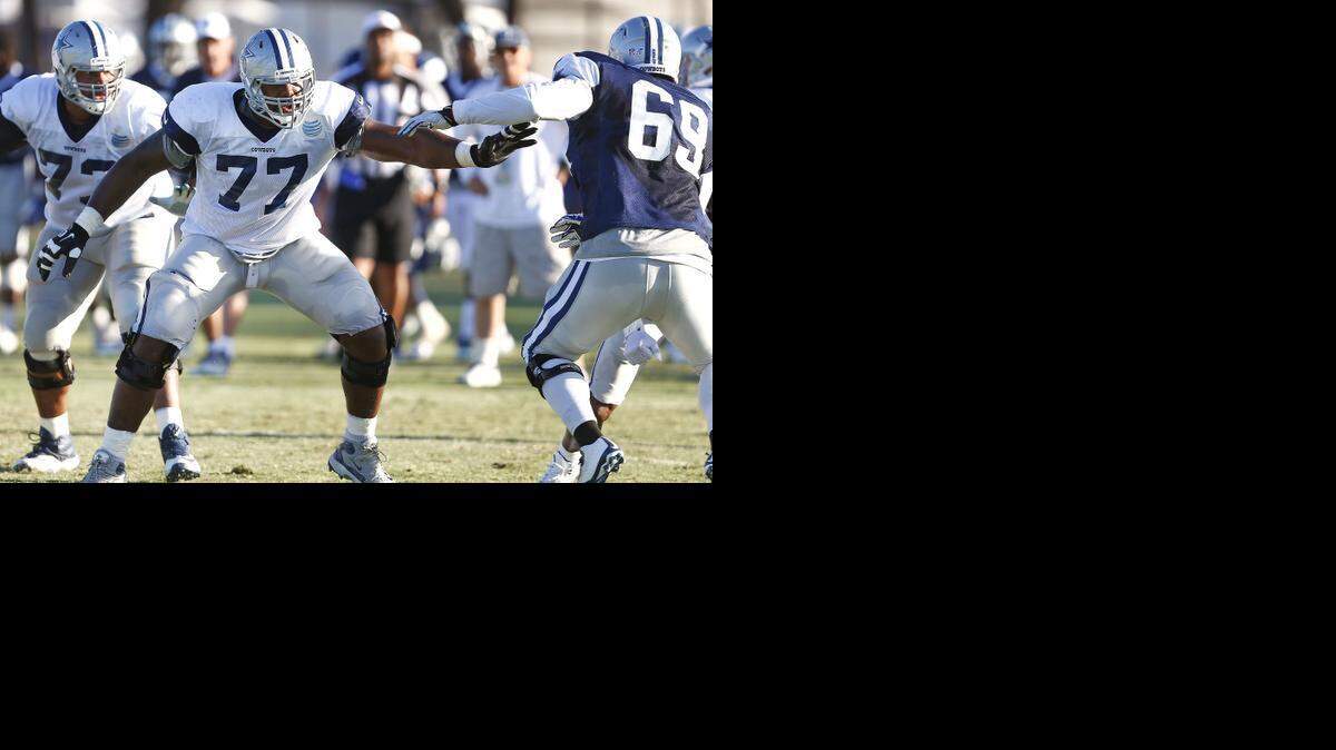 
Tyron Smith (77) blocks against Henry Melton during training camp last year. 
