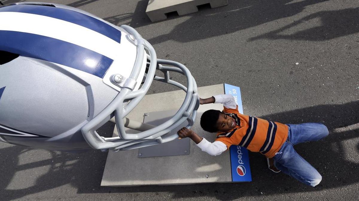 At the NFL Experience, fans will have interactive games, youth football clinics, merchandise, player autograph sessions, photos with the Vince Lombardi Trophy and sometimes an oversized Dallas Cowboys helmet like this one that 9-year old Antonio Cantey is resting against.