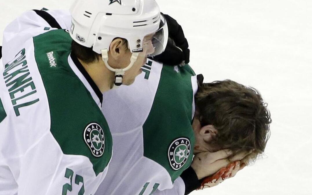 Dallas Stars left wing Curtis McKenzie holds his bloody face as he is helped off the ice by teammate Adam Cracknell (27) after getting hit by a stick in the third period Thursday against the Boston Bruins.
