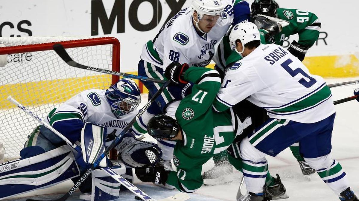 Vancouver Canucks’ Luca Sbisa (5) checks Dallas Stars’ Devin Shore (17) as goalie Ryan Miller (30) protects the net and Nikita Tryamkin (88) checks Jason Spezza (90) during the third period of an NHL hockey game, Friday, Nov. 25, 2016, in Dallas.