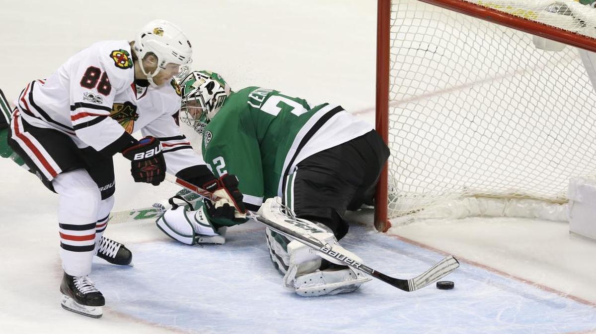 Chicago Blackhawks right wing Patrick Kane, left, slides around Stars goalie Kari Lehtonen for a game-tying goal in the third period. Chicago with score twice more in the final five minutes for a 5-3 victory Saturday.