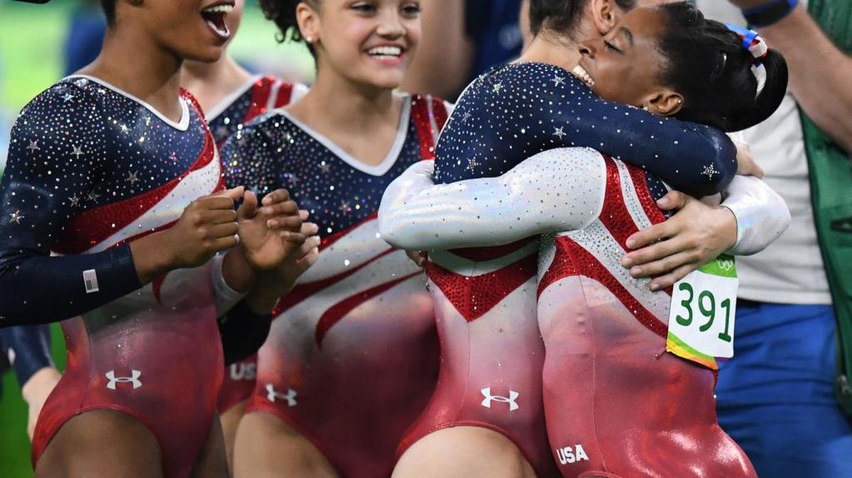 The U.S. women’s gymnastics team, from left, Gabrielle Douglas, Lauren Hernandez and Alexandra Raisman greet teammate Simone Biles after her floor routine secured the gold medal in the team competition on Tuesday, Aug. 9, 2016, at the Rio Olympic Games in Rio De Janeiro, Brazil. (Mark Reis/Colorado Springs Gazette/TNS)