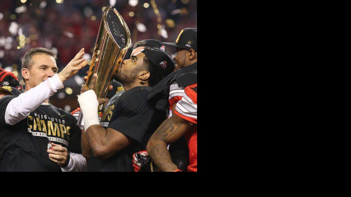 
Ohio State Buckeyes running back Ezekiel Elliott kisses the championship trophy with coach Urban Meyer at left. 
