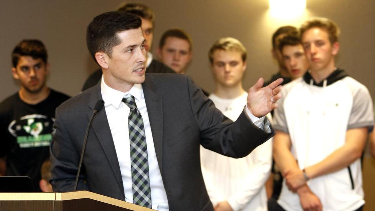 With Dragon football players in the background, Riley Dodge is introduced as the new head coach during a Carroll school board meeting March 26, 2018.