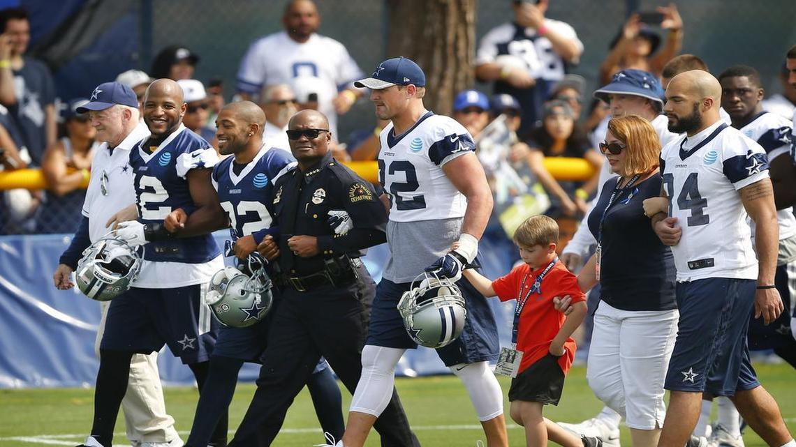 Dallas Police Chief David Brown walks arm-in-arm with owner Jerry Jones, safety Barry Church, cornerback Orlando Scandrick and tight end Jason Witten before the start of training camp. Along with them were Magnus Ahrens, 8, the son of slain police officer Lorne Ahrens and his aunt, Erika Swyryn, and tight end James Hanna.