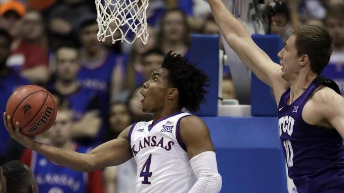 Kansas guard Devonte’ Graham (4) gets past TCU forward Vladimir Brodziansky for a second-half basket in the Jayhawks’ 71-64 win Tuesday.