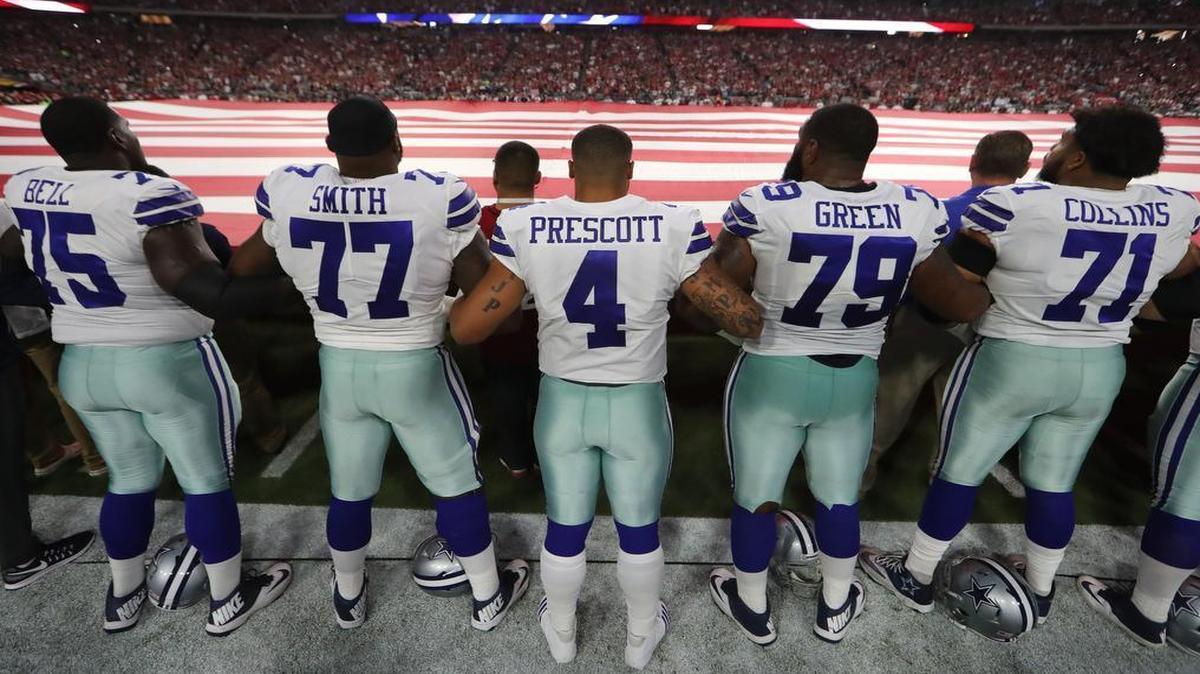 After briefly kneeling together the Dallas Cowboys stand for the national anthem before playing the Arizona Cardinals in University of Phoenix Stadium in Glendale, Arizona, Monday, September 25, 2017.